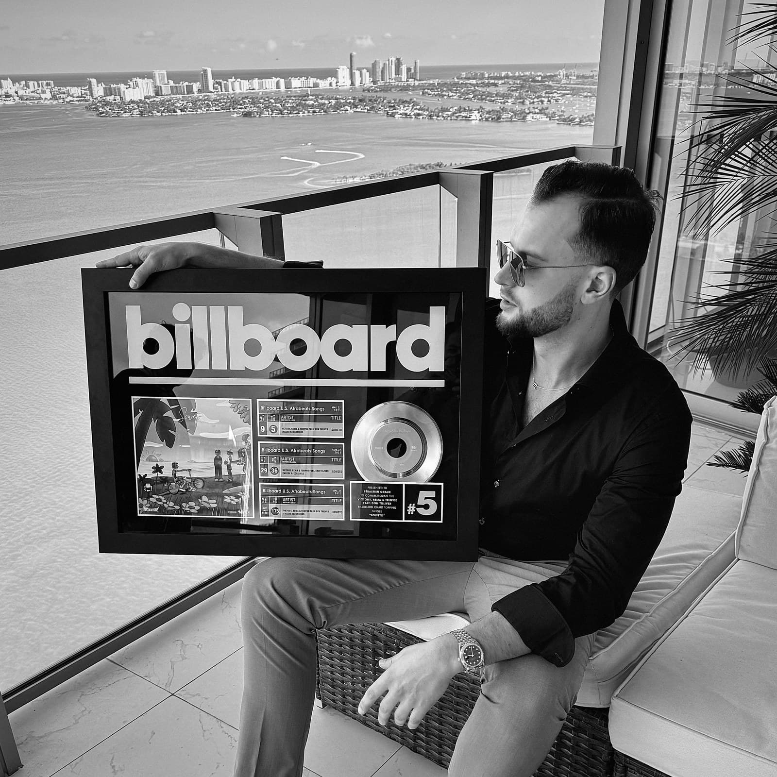 GRAUX on a Miami balcony holding his Billboard plaque